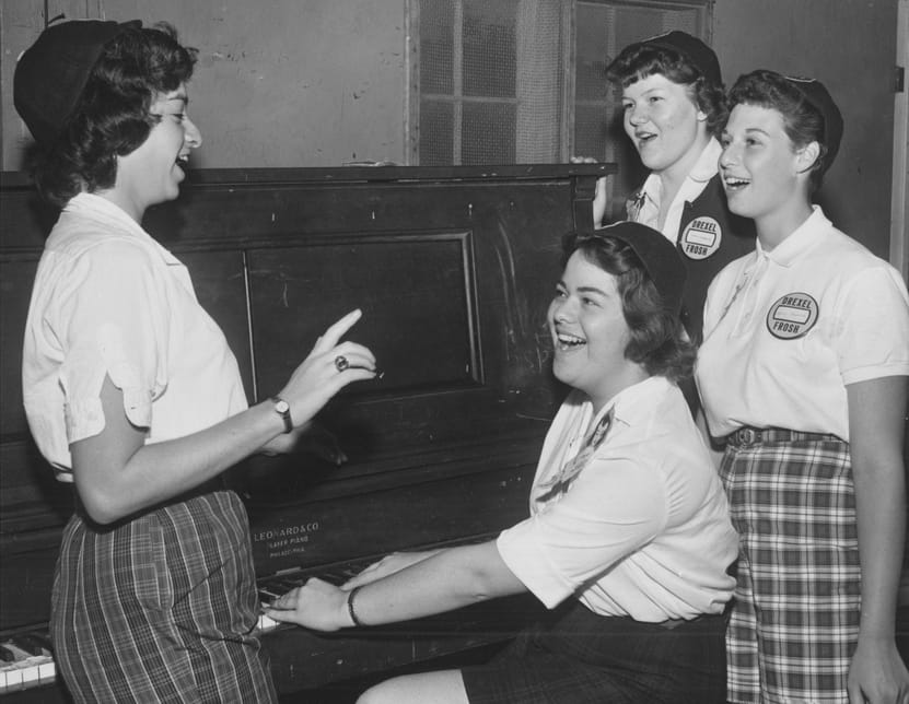 Four students wearing "dink" hats and name buttons, a common practice for freshmen from the 1940s through the 1960s. From the University Archives.