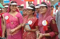 A group of women wearing visors and buttons with red ribbons for HIV awareness.